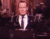 a man in a suit and tie is sitting in front of a microphone .