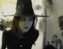 a woman wearing a black hat is standing in front of an umbrella