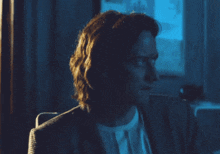 a man in a suit is sitting in front of a window in a dark room