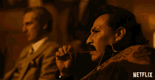 a man with a mustache is smoking a cigar with a netflix logo in the corner