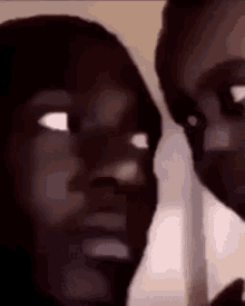 a man and a woman are standing next to each other and looking at each other with their eyes closed .