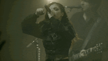 a woman is singing into a microphone while a man plays a guitar .