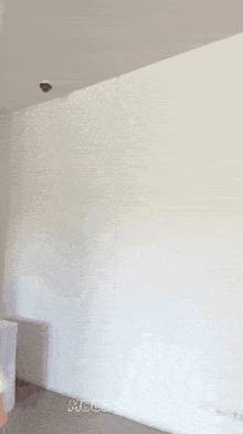 a woman is standing in front of a white wall and smiling