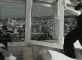 a woman is opening a window with a view of the city