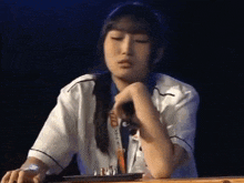 a woman sitting at a table with a lanyard around her neck that says world chess championship