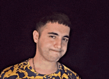 a young man wearing a yellow and blue shirt with a chain around his neck
