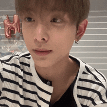 a close up of a person 's face with a striped shirt and earrings