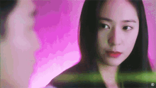 a woman and a man are looking at each other in a pink room .
