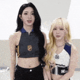 two girls are standing next to each other with one wearing a crop top with the letter t on the front