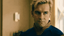 a man with blonde hair and a blue shirt is looking at the camera