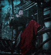 a man in a red skirt plays a flute in a dark room