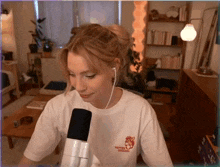 a woman wearing a white t-shirt with a tiger on it is talking into a microphone