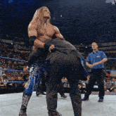 a man in a suit is being lifted by a wrestler