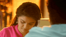 a woman in a pink shirt looks down at something while a man looks on