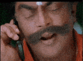 a man with a big mustache is talking on a cell phone .