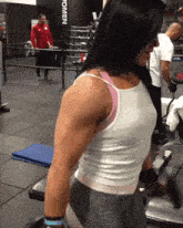 a woman lifting weights in a gym with the word women on the wall behind her