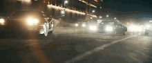 several cars are driving down a street at night with their lights on