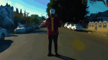a man in a red jacket is standing on a street