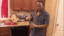 a man is standing in a kitchen holding a bottle of beer