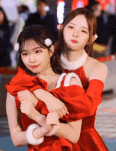 a girl in a santa outfit is hugging another girl