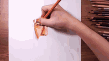 a person is drawing a face with an orange colored pencil