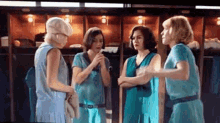 a group of women are standing next to each other in a locker room talking .