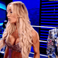 a woman in a very revealing top is standing in a wrestling ring ..