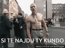 a man without a shirt is walking down a street with the words si te najdu ty kundo below him