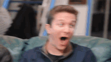 a man is sitting on a couch with his mouth open