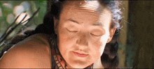 a close up of a woman 's face with her eyes closed and sweat on her forehead .
