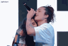 a woman is singing into a microphone while hugging another woman .