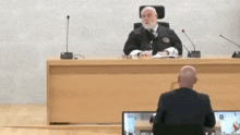 a man in a suit is sitting in front of a judge .
