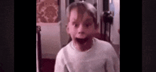 a young boy is making a funny face while standing in a room .