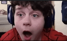 a young boy wearing blue headphones looks surprised