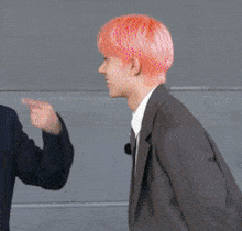 a man with pink hair is pointing to another man