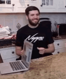 a man with a beard is sitting at a counter with a laptop and a shirt that says nigga