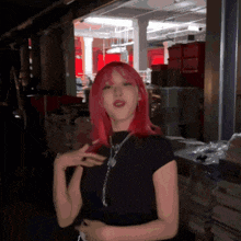 a woman with red hair and a black shirt is standing in a dark room