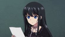 a girl with long black hair and blue eyes holding a piece of paper