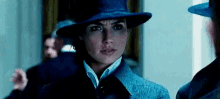 a woman wearing a hat and a coat is standing next to a man in a suit .