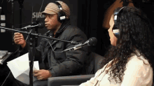 a man and a woman wearing headphones are sitting in front of microphones