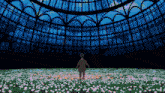 a man is standing in a field of flowers in front of a building