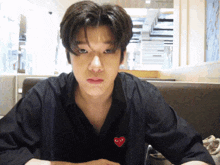 a young man wearing a black shirt with a red heart on the front