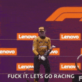 a man is holding a trophy and a bottle of champagne in front of a lenovo sign .