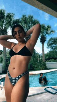 a woman in a bikini is standing in front of a swimming pool
