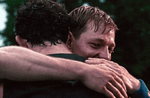 two men hugging each other with their arms around each other 's necks