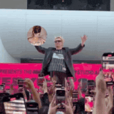 a man in a suit stands in front of a crowd of people taking pictures of him