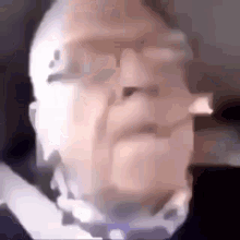 a blurry picture of a man with glasses and a bow tie .