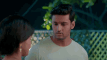 a man in a white shirt looks at a woman