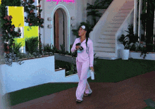 a woman in pink pajamas is walking in front of a building with a neon sign that says " i love you everybody "
