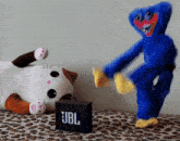 a blue stuffed animal dancing next to a jbl box